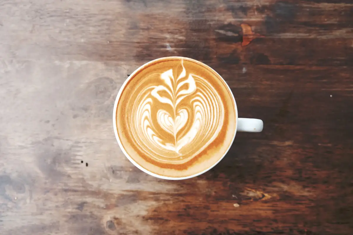 Flat white con arte latte servido sobre una superficie de madera
